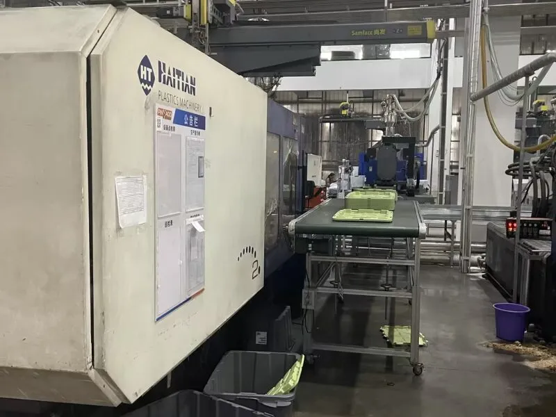 Injection molding machine producing plastic crates for automated warehouse integration.