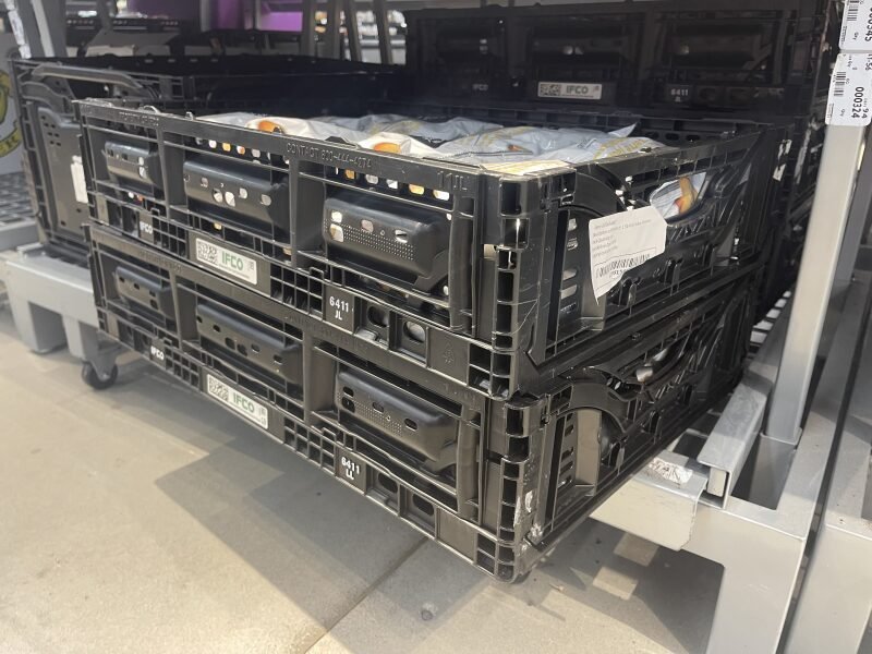 Black plastic crates in a post - harvest handling center, used for storing goods.
